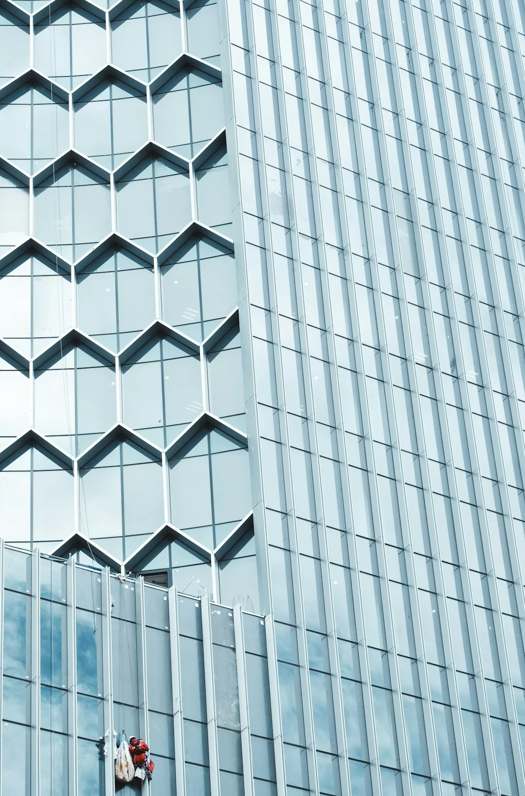Two workers hanging to clean windows on a modern skyscraper facade.
