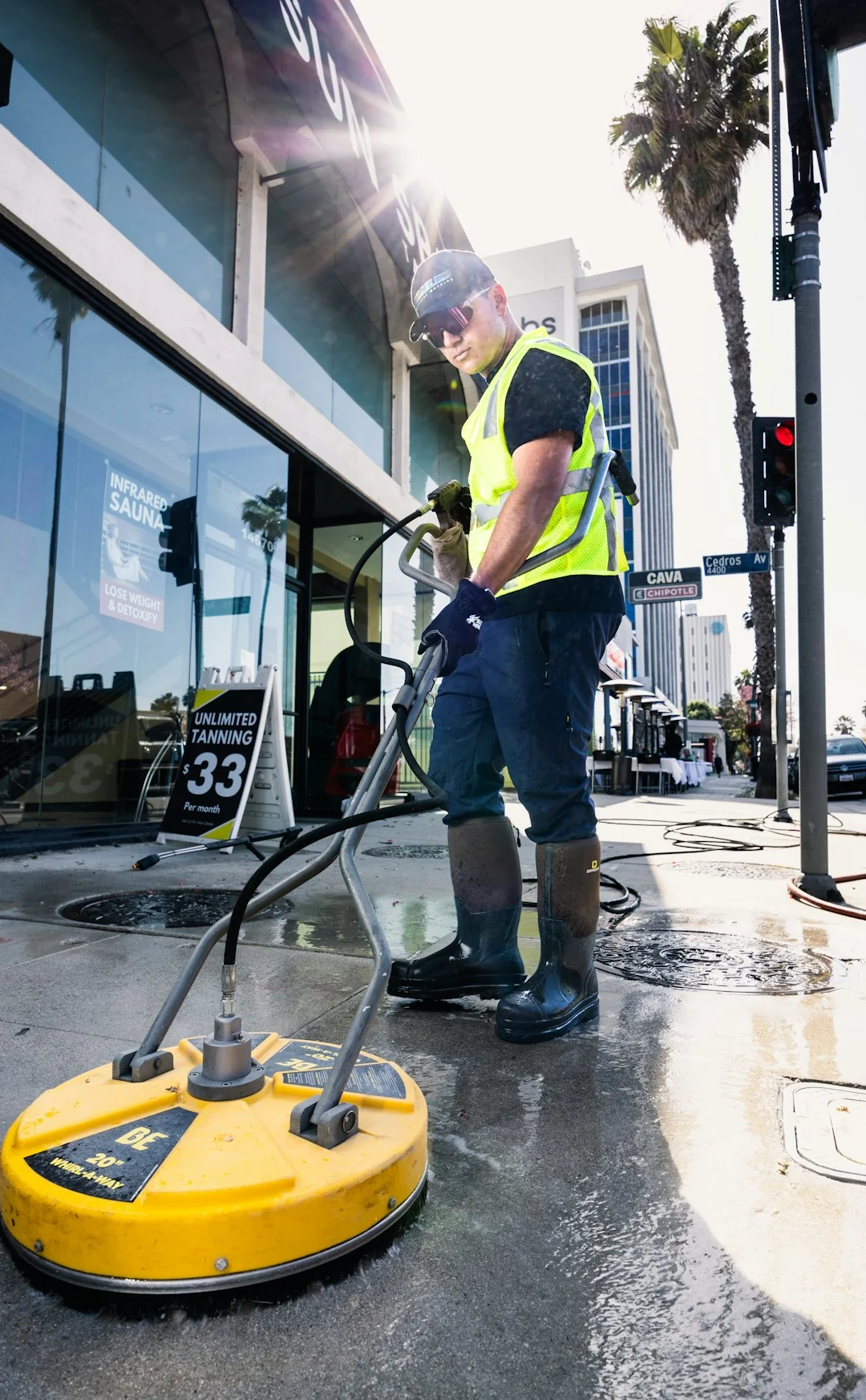 Two workers clean windows on a modern glass building facade using a suspended platform.