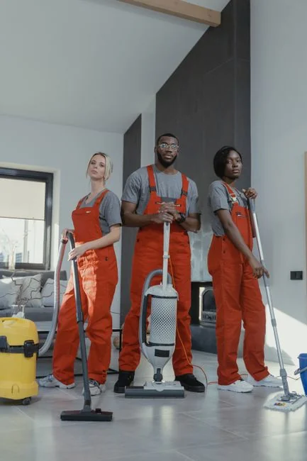 Three rope-suspended window cleaners wash the glass exterior of a modern building in daylight.